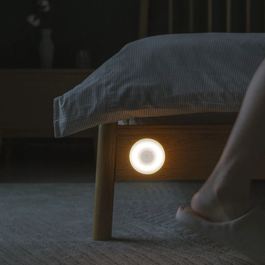 White modern bedside table lamp with human body induction and Bluetooth on a wooden nightstand.