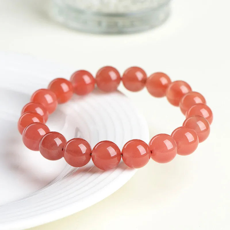 Natural South Cherry Red Agate beaded bracelet on a wrist, showing polished scattered beads on an elastic cord.