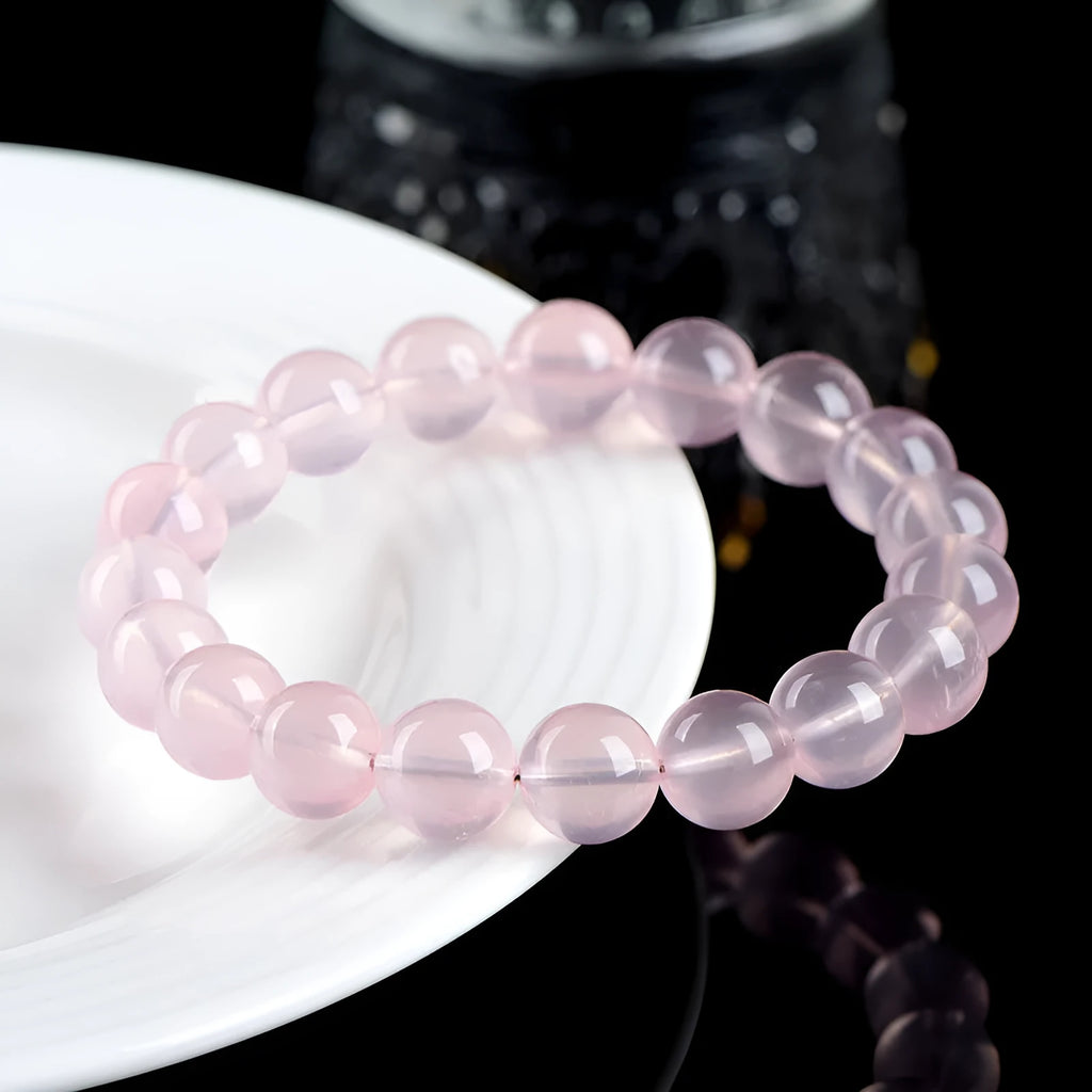 Women's natural starlight crystal round bead bracelet in pink on a white background.