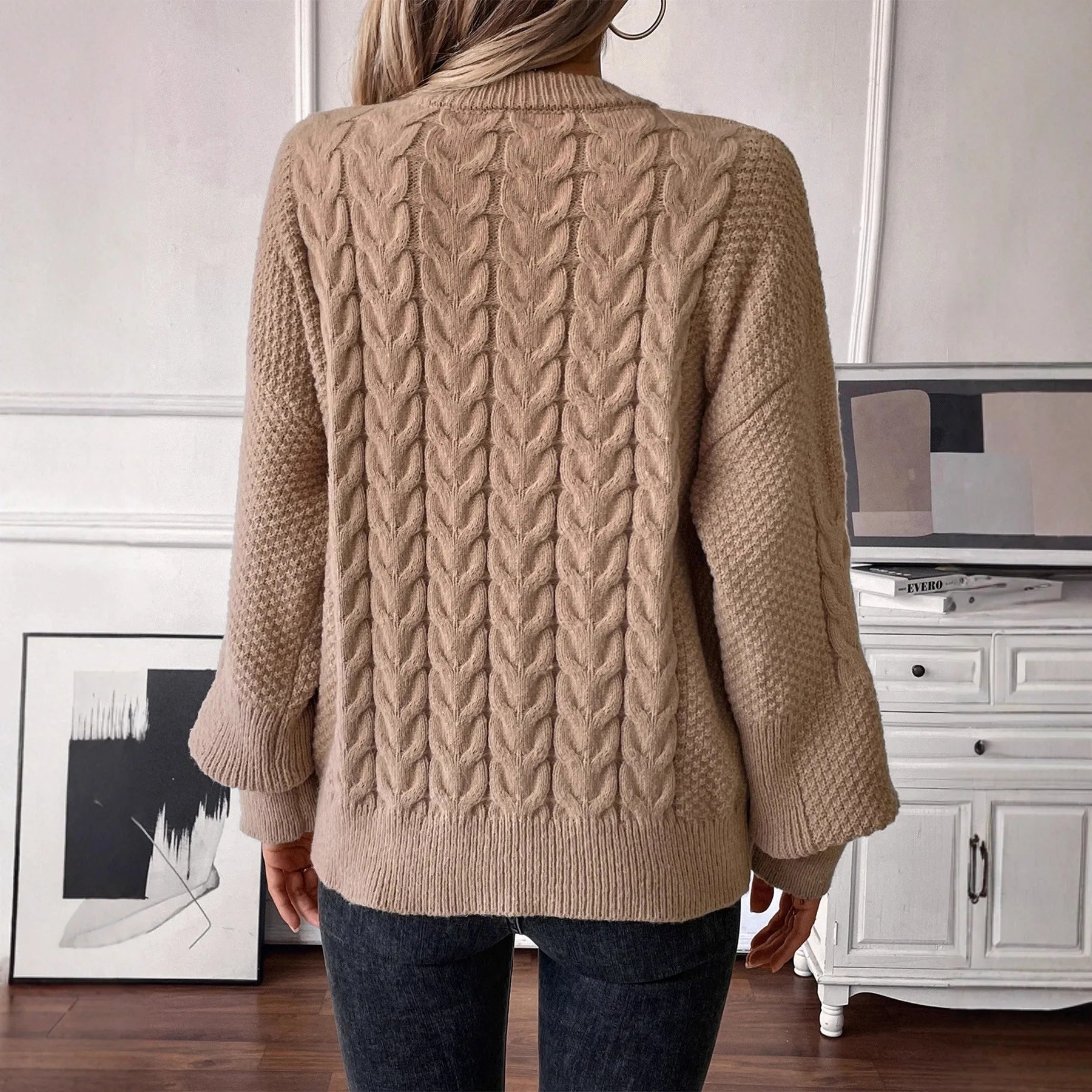 A woman's loose-fit round neck sweater in a solid colour, shown in a casual street fashion style.