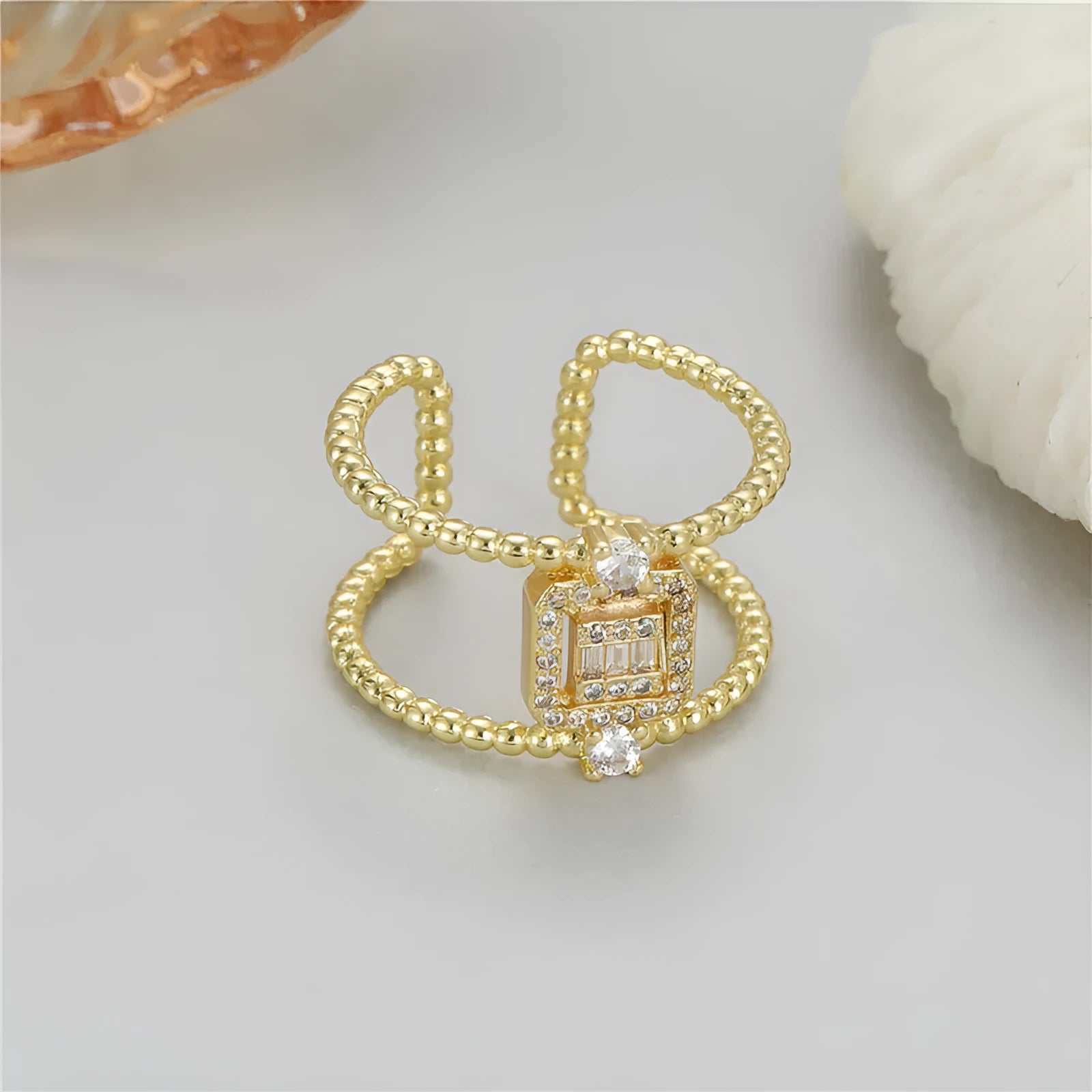 Copper open ring with 14K gold plating in an asymmetrical U-shape on a plain background.
