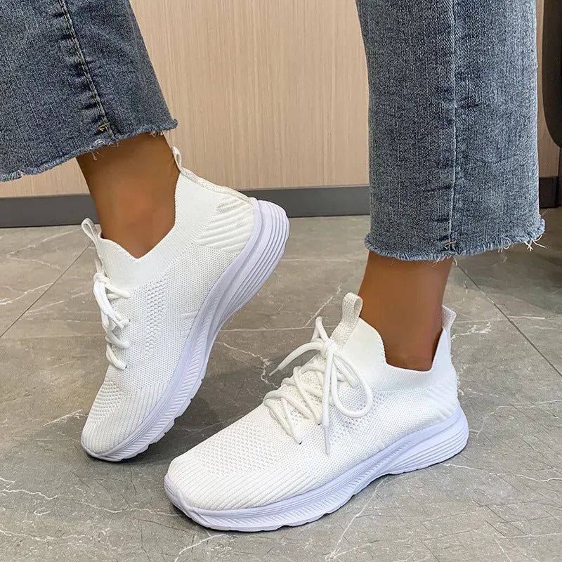 Women's low-top running shoes in creamy white with Flyknit upper and flat rubber sole.