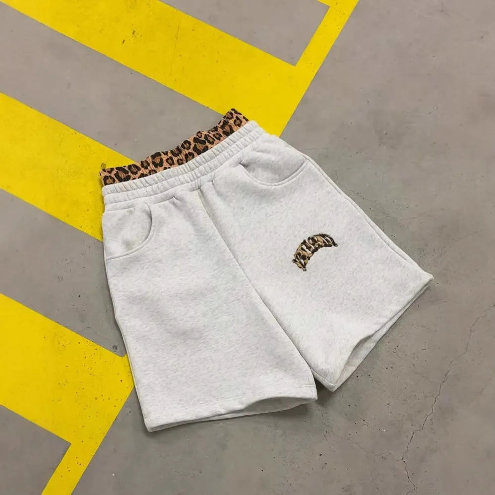 Men's grey patchwork loose hip hop trousers with elastic waist and zip fly on a plain background.
