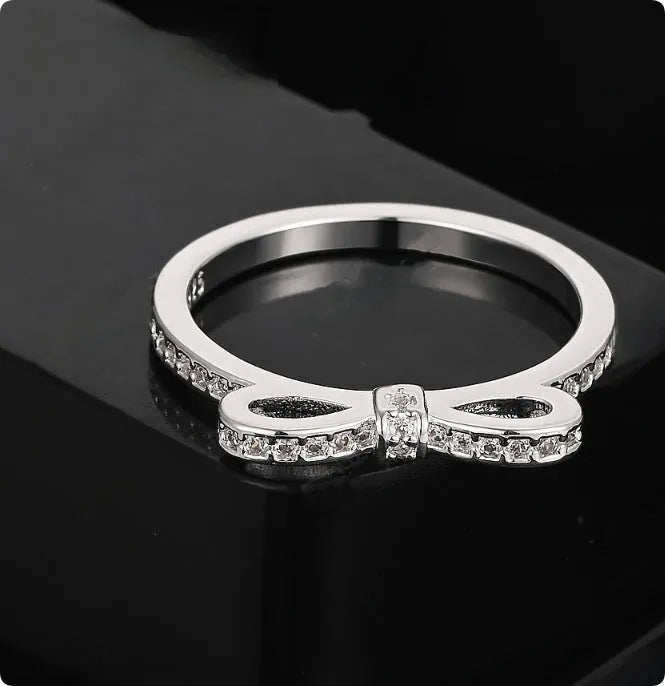 Silver bow-shaped ring with crystal zircon and rhinestone detailing on a finger