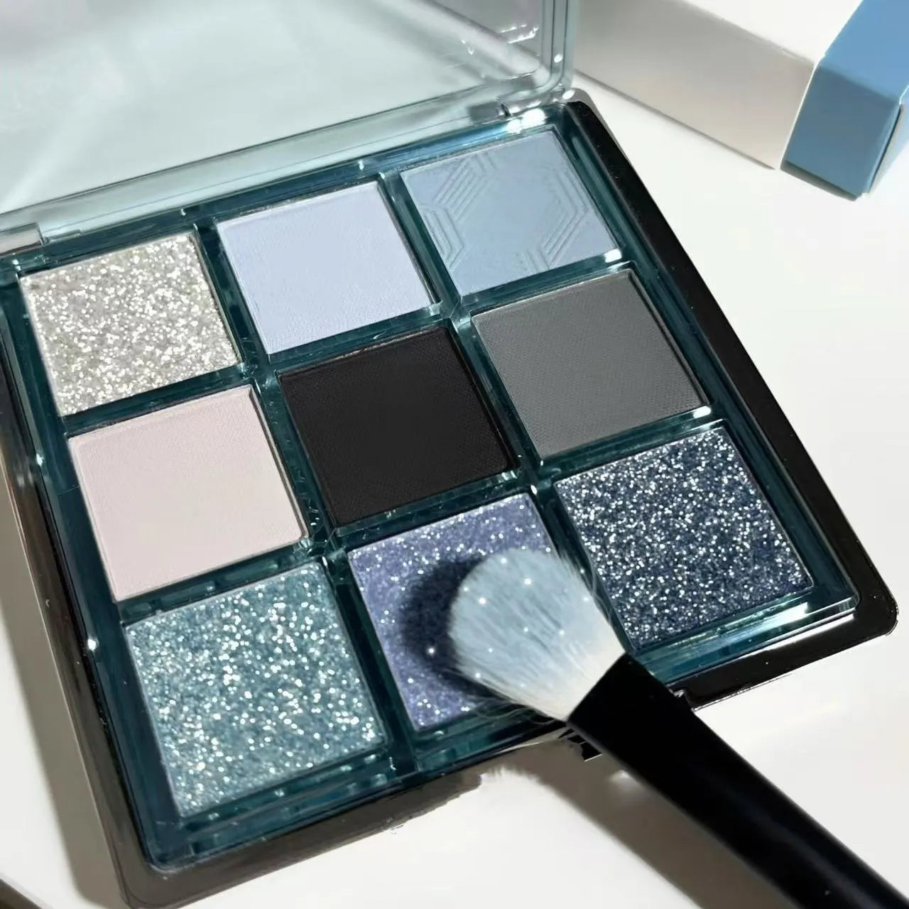MUGELEEN nine-colour eye shadow palette showing earth tones with blue smoked variations