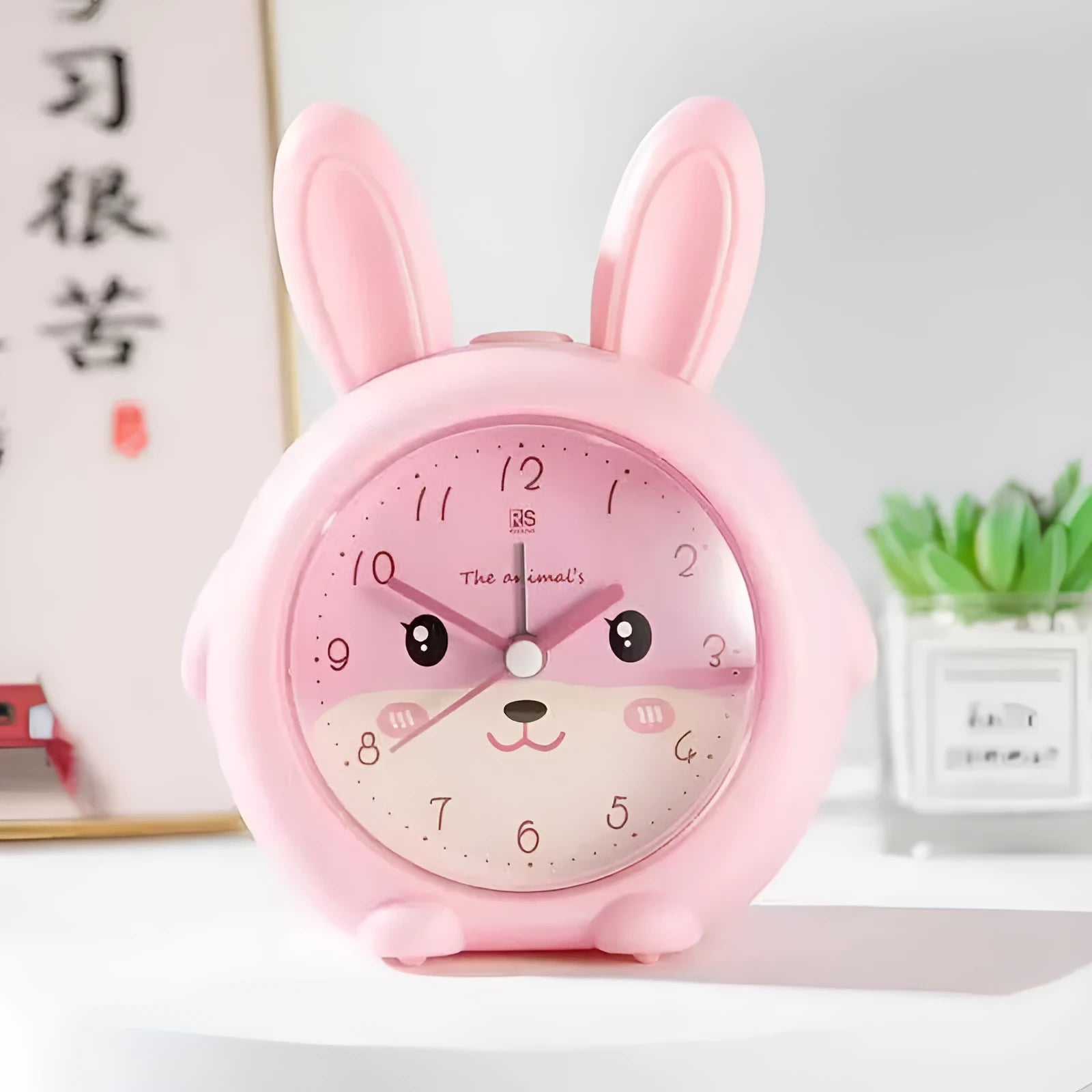 Pink and blue cartoon children's alarm clock with night light on a bedside table.