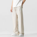 Men's beige loose straight-leg linen trousers with a drawstring waist on a neutral background.