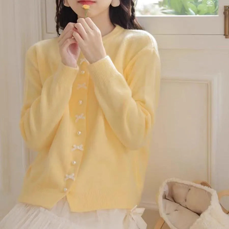 Women's solid colour cardigan with a bow and pearl buttons, in a light yellow acrylic knit.