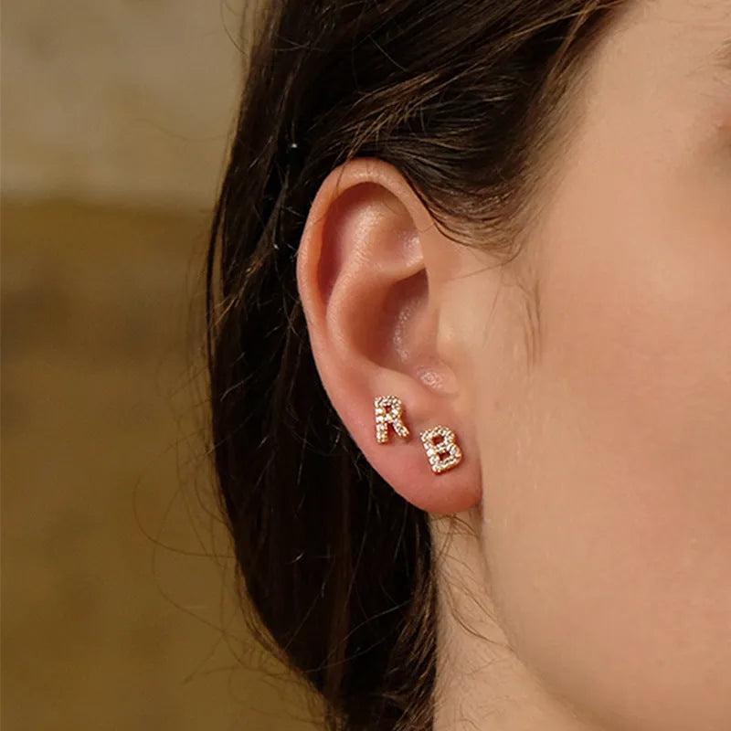 Gold plated alphabet letter earrings on a white background showing the letter A with zircon stones and butterfly backings.
