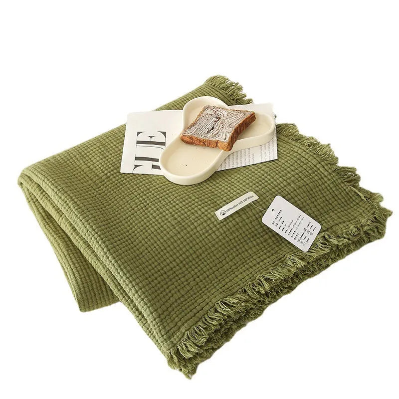 Four-layer gauze cotton blanket with tassel trim in navy blue colour laid flat