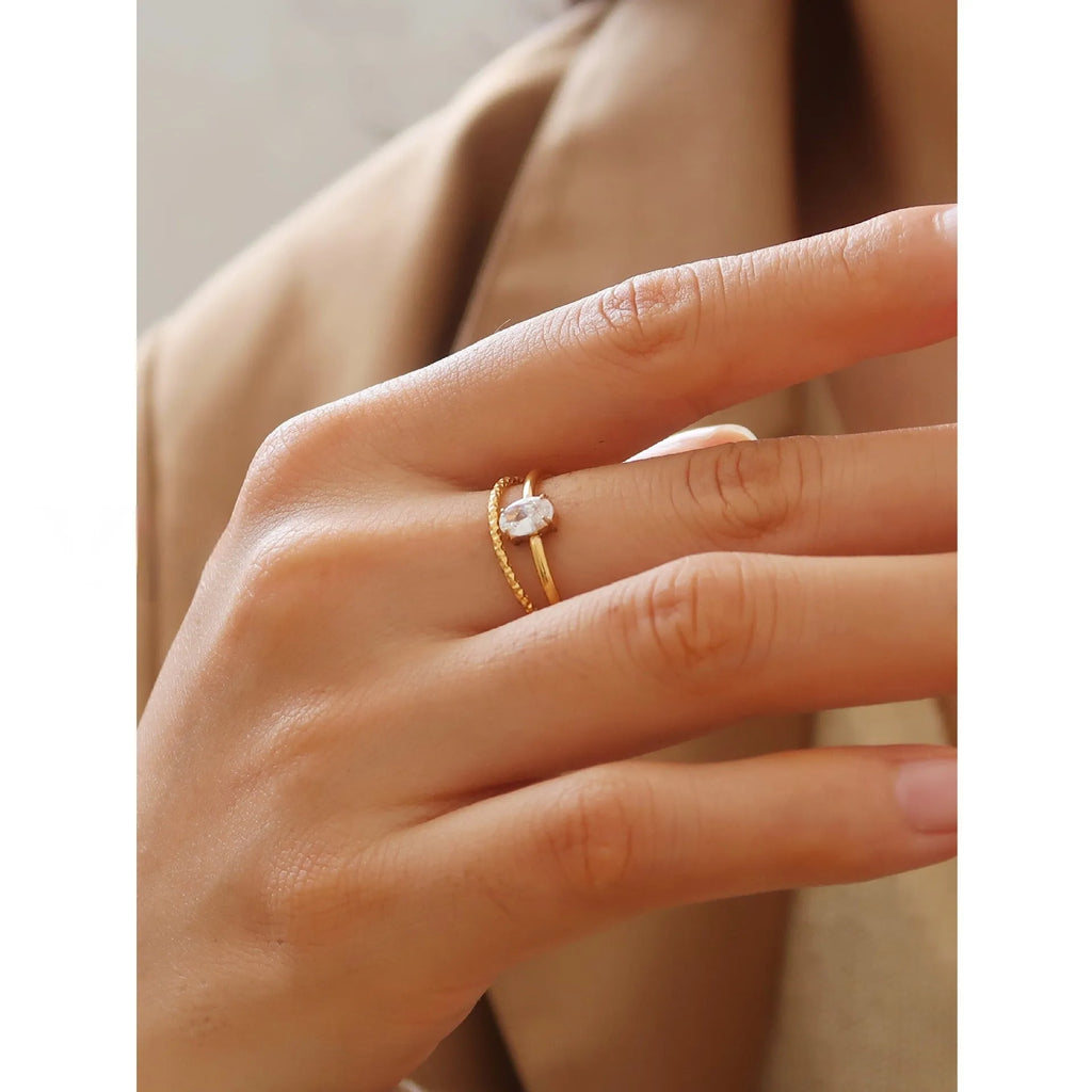Golden electroplated stainless steel ring showing heart shape and oval charm design on female hand