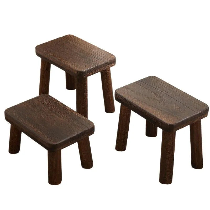 Solid wood distressed finish changing stool with bracket legs on a wooden floor.