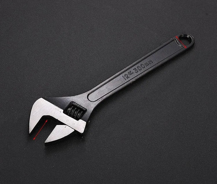 Blackened high carbon steel adjustable open-end wrench on a workbench, jaw set to mid-opening.