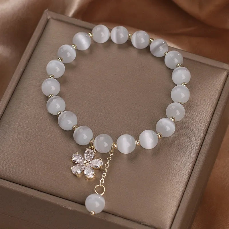 Women's white cat's eye crystal bracelet with floral tassel design and safety buckle pendant