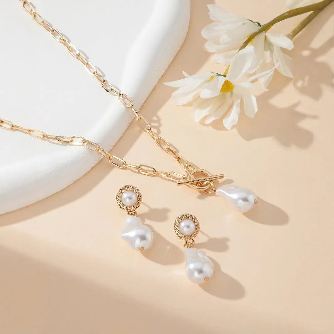 Gold tone baroque pearl pendant necklace and matching ear stud set on display