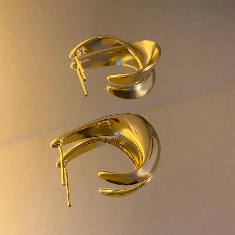 Geometric twisted metal earrings with electroplated gold or silver finish and round design elements