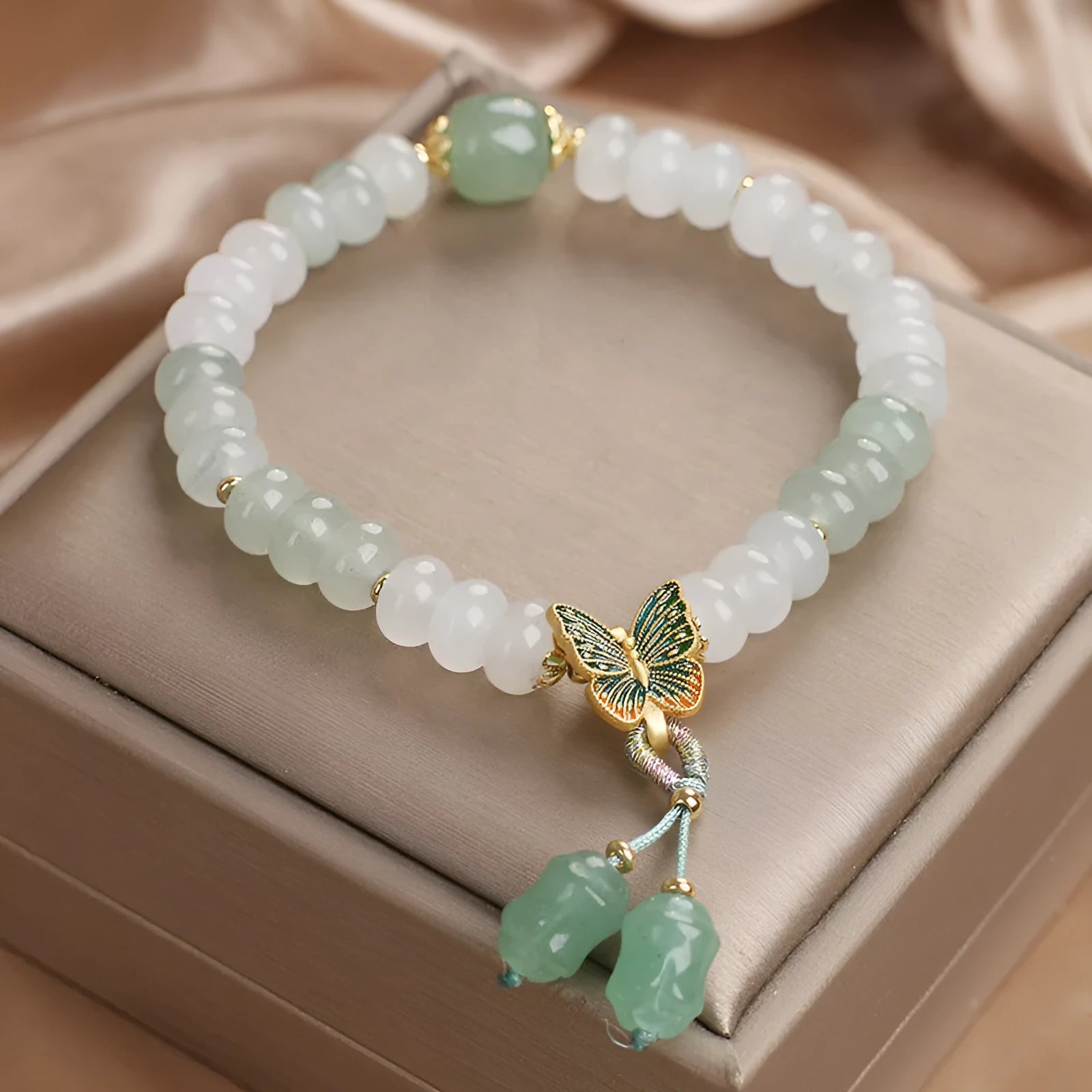 Tian Shan Cui green crystal abacus beads bracelet with butterfly tassel, pearls, and rhinestones on white background