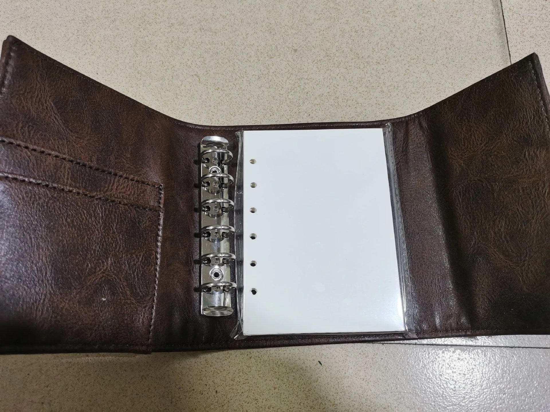 Brown A7 notebook with retro leather buckle closure showing loose-leaf binding