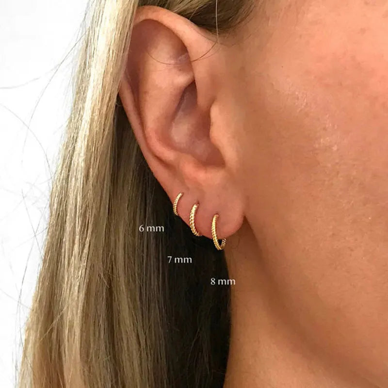 Close-up of twisted sterling silver hoop earrings showing the textured string design.