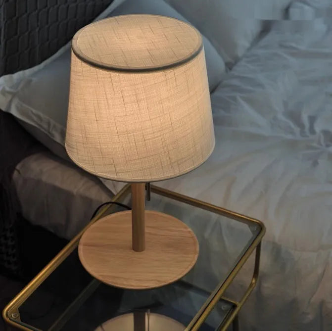 Walnut-coloured solid wood bedside lamp with white cloth shade and cable switch
