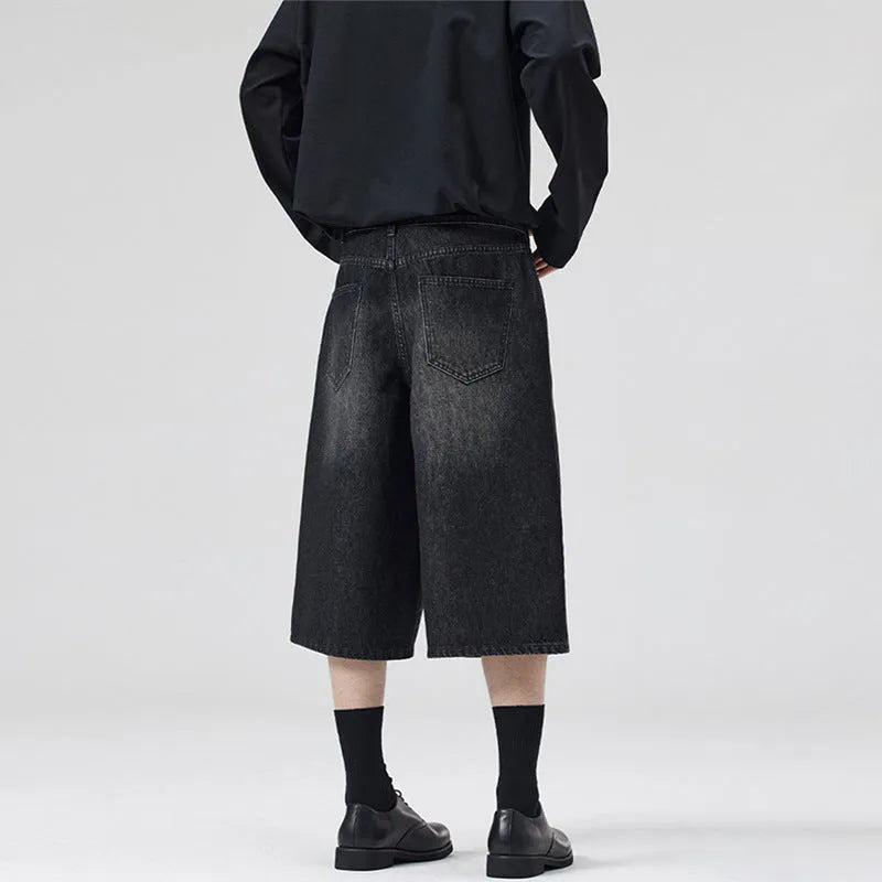 Man wearing loose straight-leg cotton denim shorts in a summer casual setting.