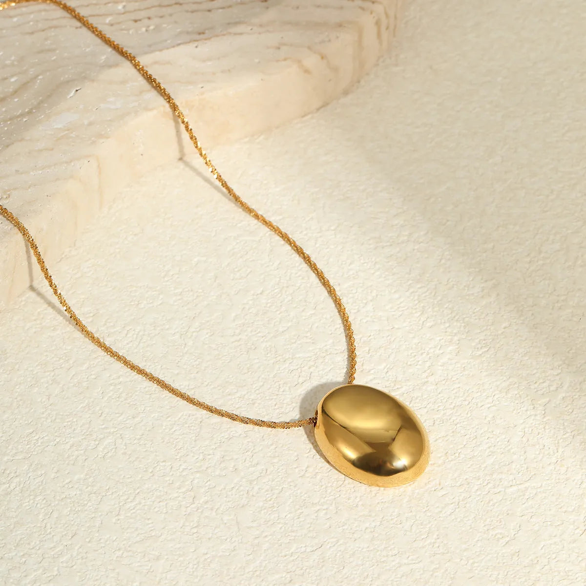 Gold-plated necklace with geometric pendant on stainless steel chain, showing 18K plating and adjustable length