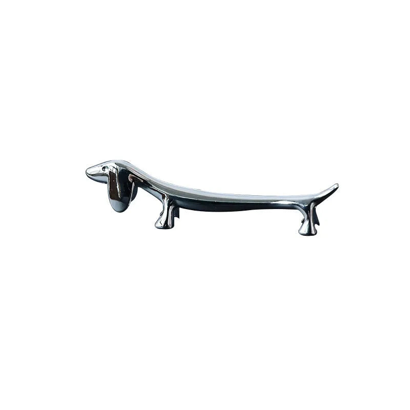 Silver zinc alloy sausage dog chopstick rest knife holder on desk with pen and chopsticks