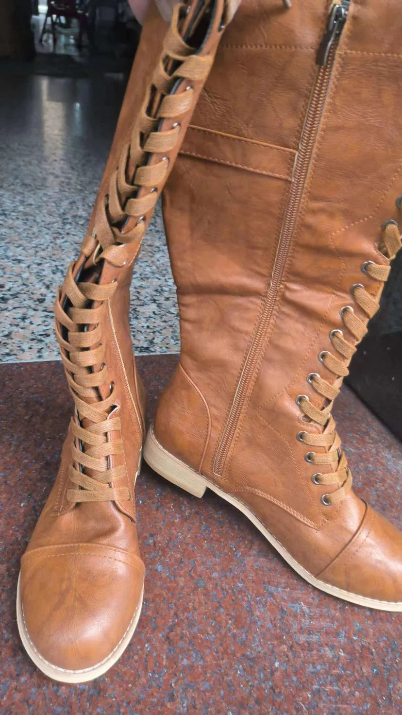 Women's black knight-style ankle boots with a cross-strap design across the front.