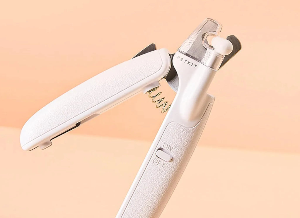 White pet nail clippers with LED light, transparent guard, and a separate nail file on a plain background.