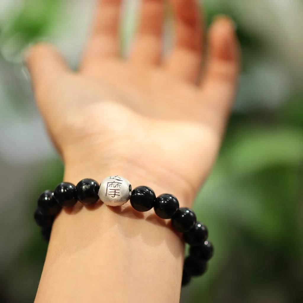 Close-up of a black agate and sterling silver bracelet with 10mm beads and Chinese style design.
