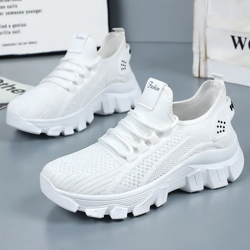 Women's white Flyknit sneakers with thick PVC sole and lace-up fastening on a neutral background.