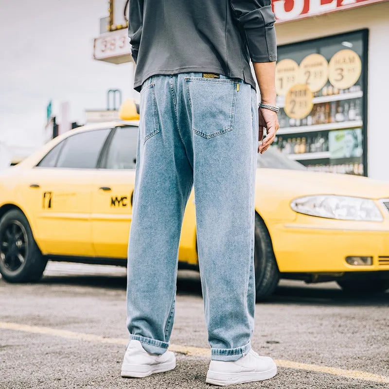 Men's loose straight fit casual jeans in dark blue cotton fabric, showing mid waist and zipper fly.