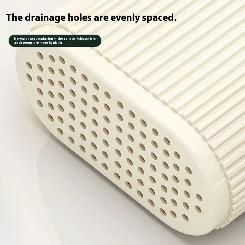 Plastic wall-mounted chopstick holder in beige with drainage holes, containing chopsticks and spoon