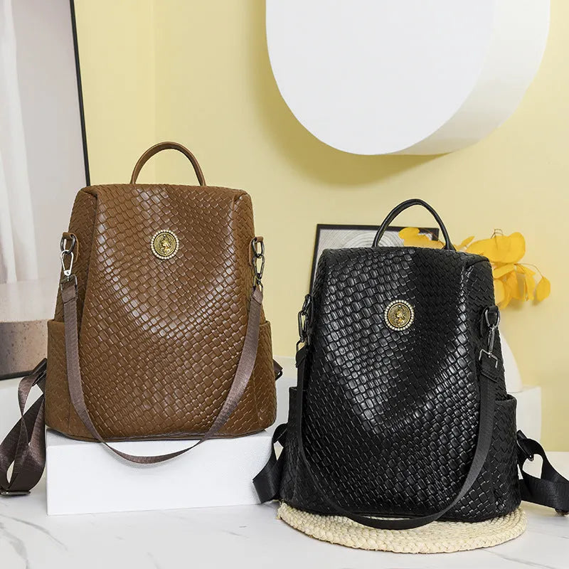 Women's large capacity anti-theft backpack in black PU material with contrast stitching and woven accents for travel