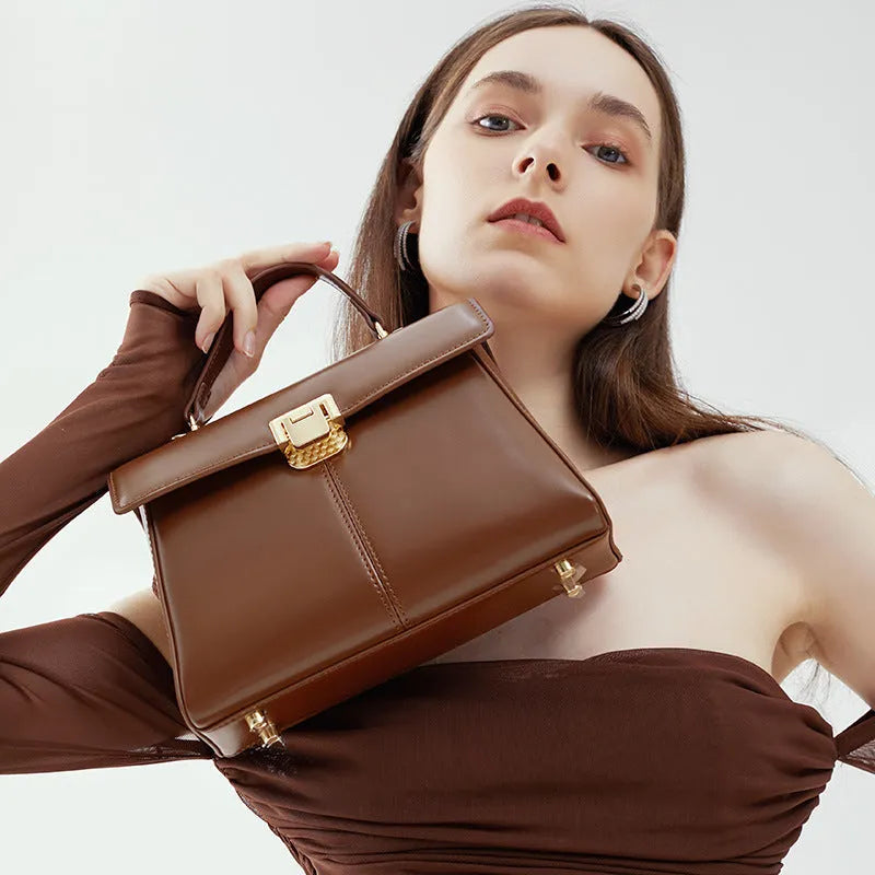 Black leather women's shoulder bag with vachette clasp showing square shape and adjustable strap.