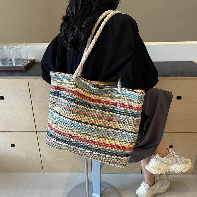 Blue woven shoulder bag with straw and nylon construction showing adjustable straps and textured exterior