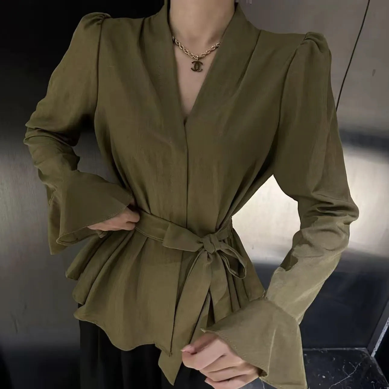 Women's black French-style shirt with an irregular collar and long bell sleeves, showing the tied front closure.