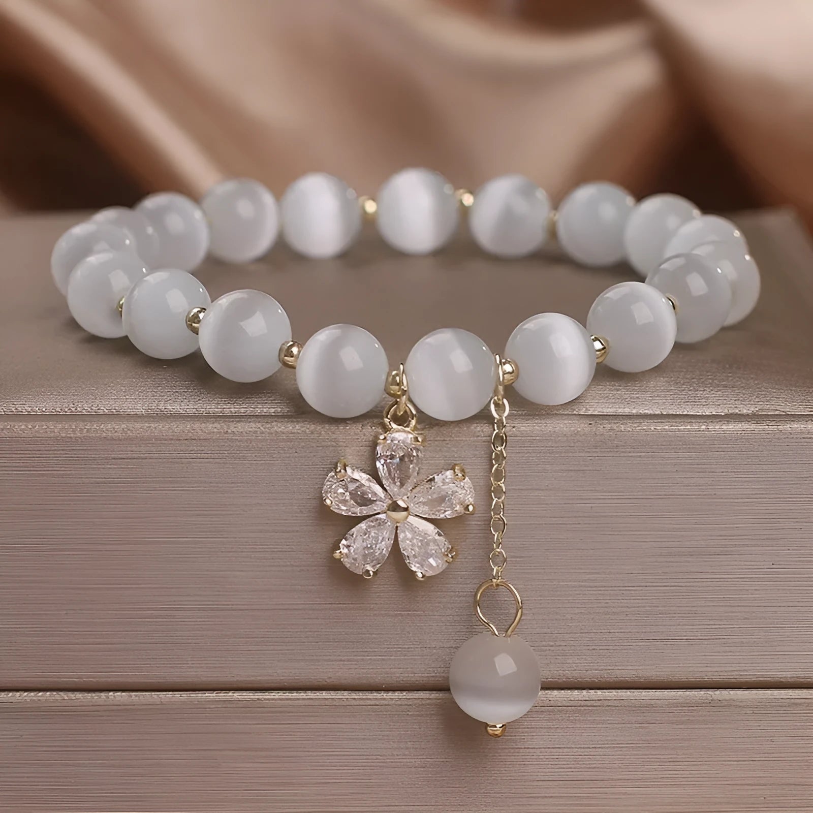 Women's white cat's eye crystal bracelet with floral tassel design and safety buckle pendant