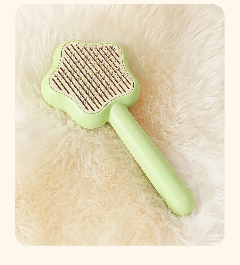 Green handled self-cleaning pet comb with stainless steel teeth on a white background.