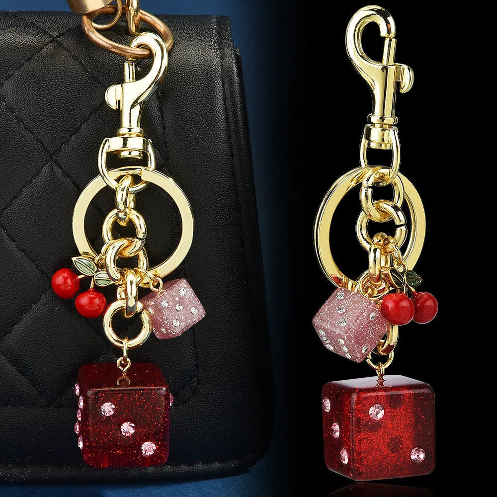 Square metal keychain pendant with a vintage red and white cherry dice pattern.