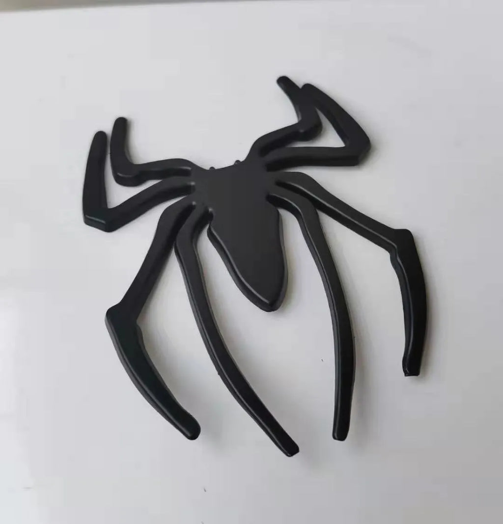 Three-dimensional metal spider bumper sticker in silver finish, measuring 7cm by 5cm.