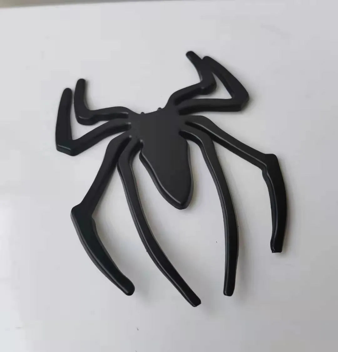 Three-dimensional metal spider bumper sticker in silver finish, measuring 7cm by 5cm.