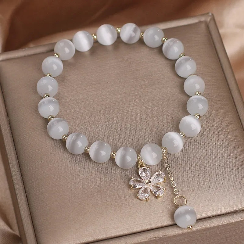 Women's white cat's eye crystal bracelet with floral tassel design and safety buckle pendant