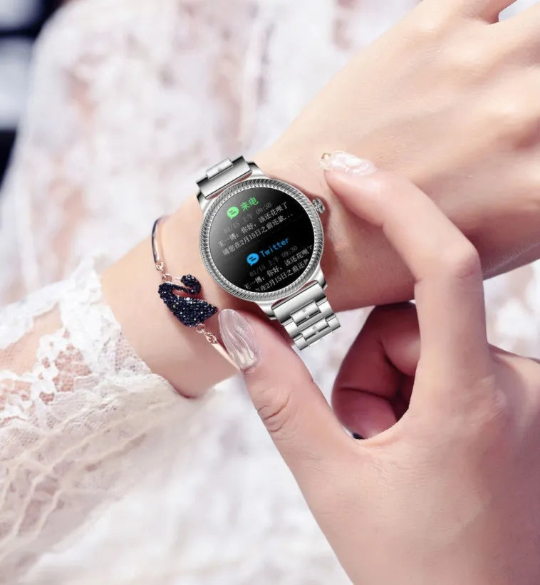 AK38 ladies smart watch with stainless steel band showing on wrist, screen displaying time.
