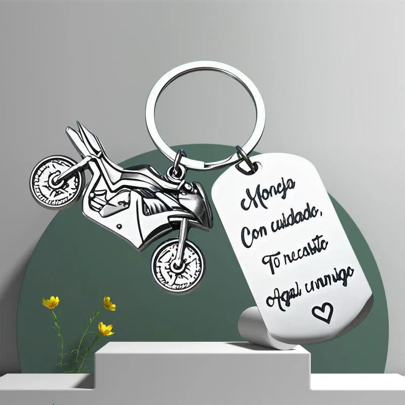 Stainless steel motorcycle-themed keychain with inspirational text alongside a flannel storage pouch.