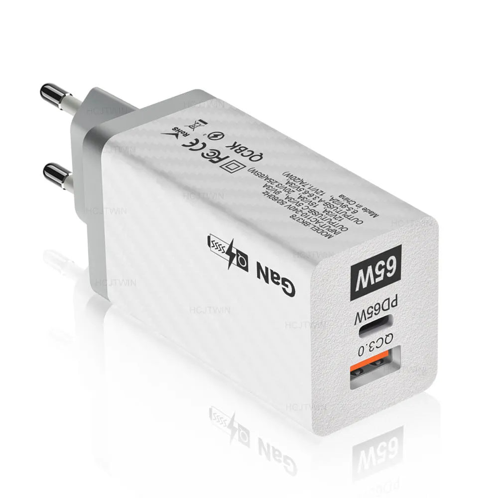 White and black 65W GaN universal laptop charger with USB-C port showing EU, UK, and US plug options