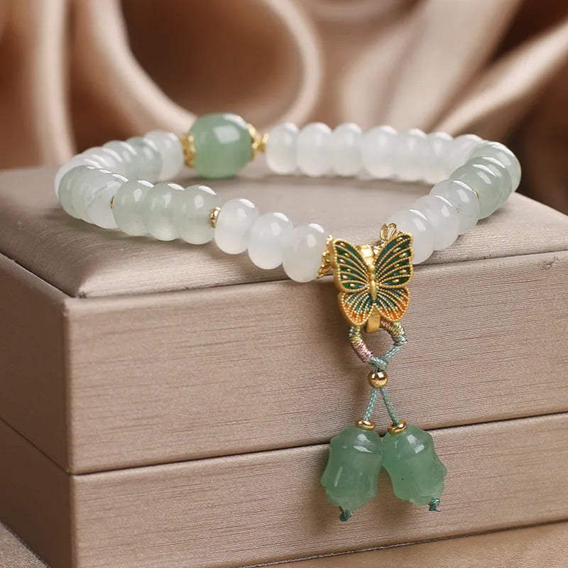 Tian Shan Cui green crystal abacus beads bracelet with butterfly tassel, pearls, and rhinestones on white background
