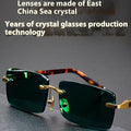 Frameless sunglasses with dark green tinted lenses lying on a hard protective case with a microfiber cloth.