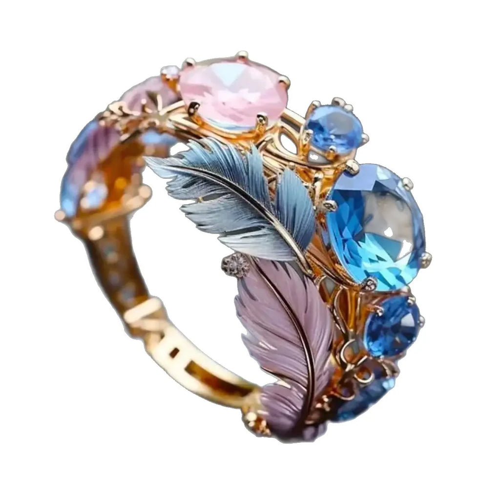 Gold-colour geometric brass ring with embossed feather design and inlaid zircon stone.