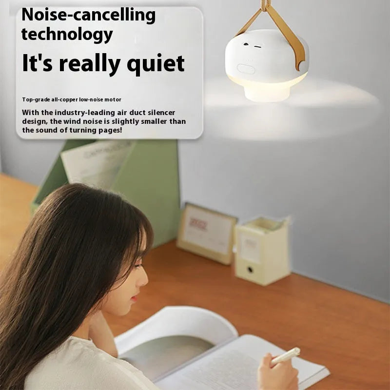Small rechargeable electric fan for camping tent with night light on, hanging from a strap